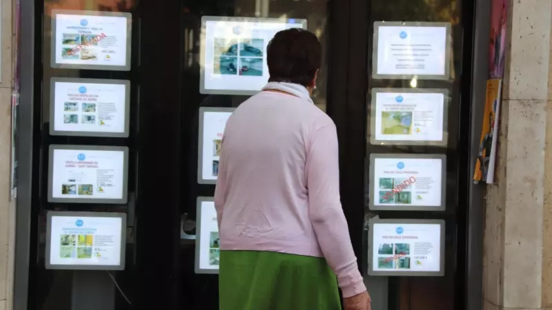 Una dona revisa les ofertes de pisos a la venda fora d'una immobiliària