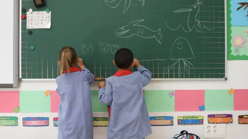 Dos niños pintan en una pizarra el día de inicio del curso en el colegio de la Alameda de Osuna, a 5 de septiembre de 2022, en Madrid (España).