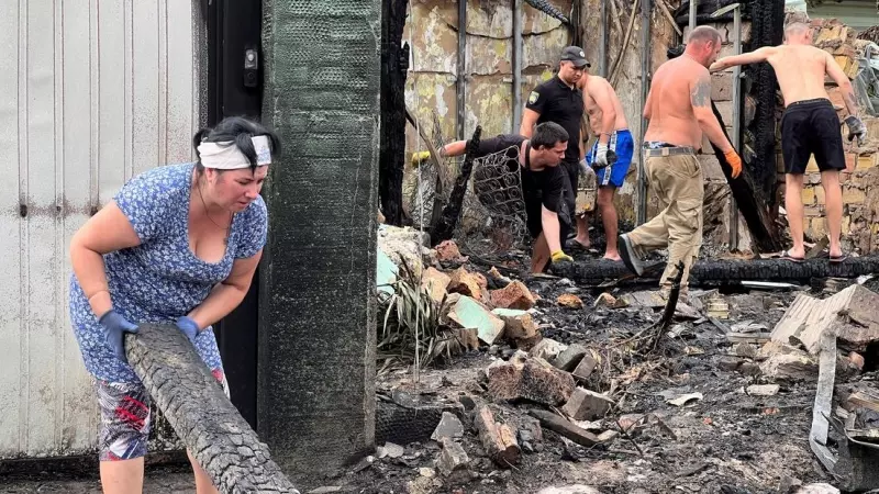 Residentes locales retiran escombros de edificios dañados por un ataque con misiles rusos en Tarasivka.