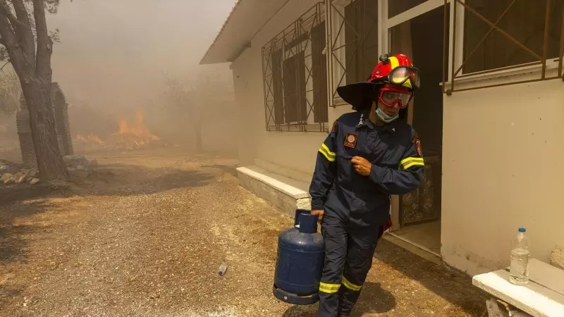 Un bombero griego retira una bombona de gas de una vivienda ardiendo en la región de Evros, asolada por el mayor incendio registrado en la historia de la UE.