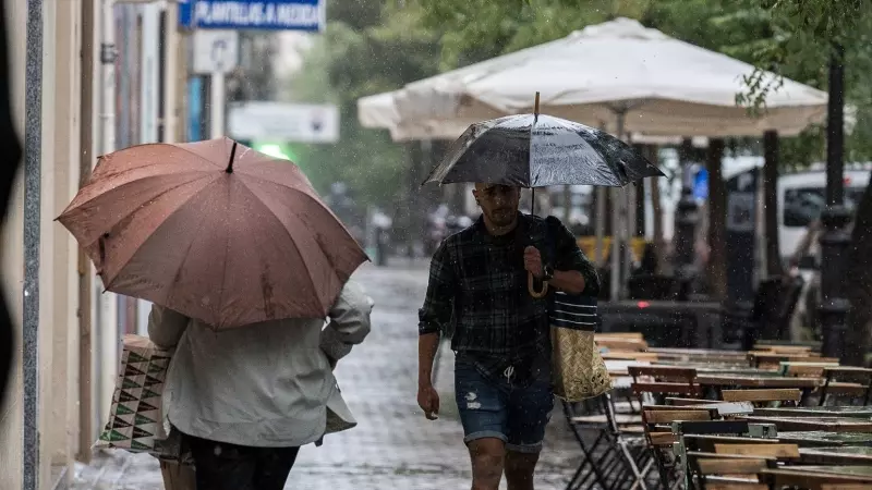 Varias personas se resguardan de la lluvia con paraguas, a 3 de septiembre de 2023, en Madrid
