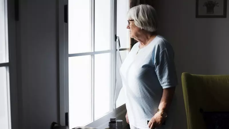 Una mujer mayor mira por una ventana (Archivo)
