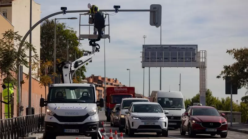 Un técnico monta una cámara de tráfico en un semáforo para controlar el acceso a la Zona de Bajas Emisiones (ZBE) de Madrid.