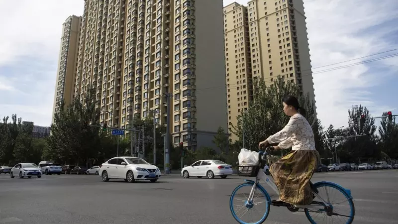 Una mujer pasa en bicicleta por un complejo de viviendas de Evergrande en Pekín. EFE/EPA/ANDRÉS MARTÍNEZ CASARES