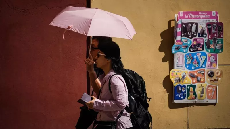 Varias personas pasean por la judería de Córdoba, protegidas por un paraguas del sol, a 29/09/2023.