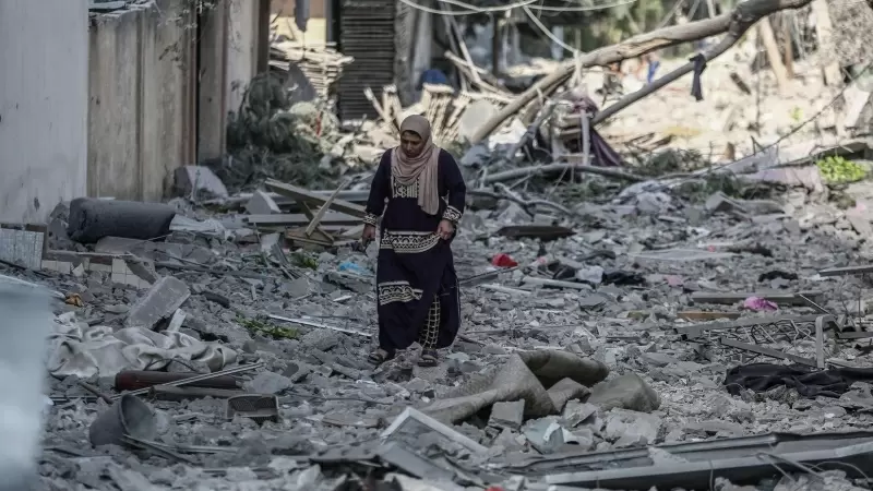Una mujer palestina recorre una calle de la ciudad de Gaza cubierta de escombros por los bombardeos de la aviación israelí, que se mantienen por quinto día consecutivo.