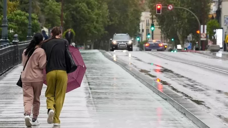 Dos personas caminan con dificultad por Sevilla debido al viento y la lluvia, a 19 de octubre de 2023.