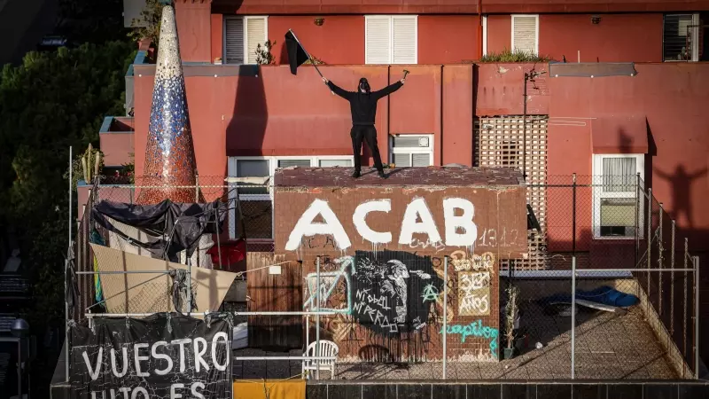Un ocupa oneja una bandera negra al terrat d'El Kubo, un dels dos edificis desallotjats aquest dijous.