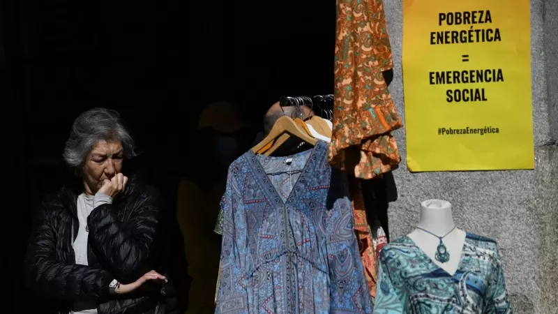 Una mujer, en un tienda de ropa con un cartel que reza 'Pobreza Energética = Emergencia Social', en una imagen de archivo.