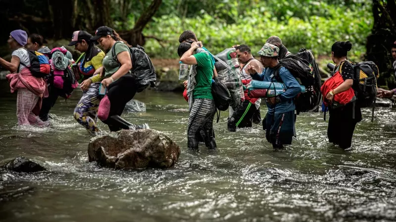 Un grupo de migrantes atraviesa un río durante su travesía por la selva del Darién, que separa Colombia de Panamá.