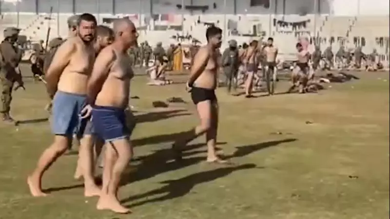 Palestinos detenidos por las tropas israelíes, caminan maniatados en ropa interior en un estadio de fútbol de Gaza.