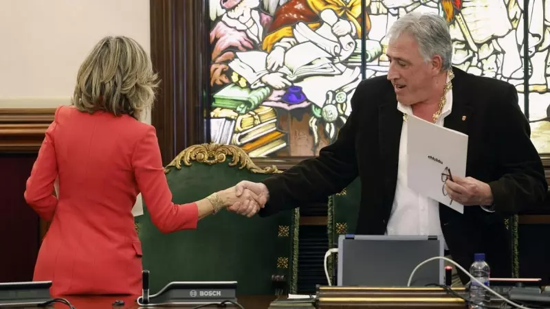 El diputado de EH Bildu, Joseba Asiron (d) estrecha la mano a su predecesora en el cargo, Cristina Ibarrola (i) tras proclamarse alcalde de Pamplona tras la moción de censura en el Ayuntamiento de Pamplona.