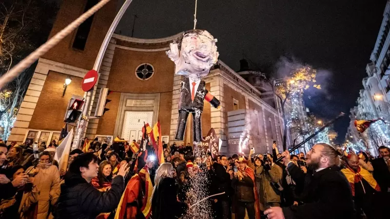 Decenas de personas celebran la entrada del año nuevo en la calle Ferraz golpeando un muñeco de Pedro Sánchez, a 1 de enero de 2024, en Madrid.