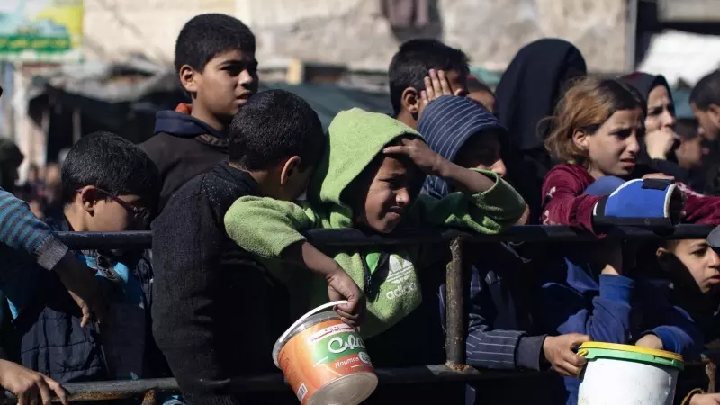 Decenas de niños palestinos desplazados se agolpan para recibir algo de comida en el campo de refugiados de Rafah, en el sur de Gaza, este 25 de enero de 2024.
