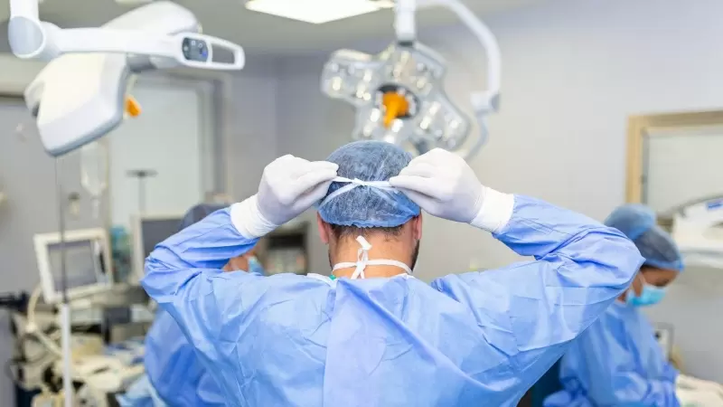 Vista trasera del cirujano masculino con mascarilla quirúrgica en el quirófano del hospital