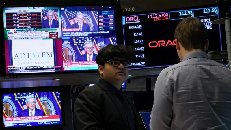 Trabajadores en la Bolsa de Nueva York mientras las pantallas muestran la rueda de prensa  del presidente de la Junta de la Reserva Federal, Jerome Powell.