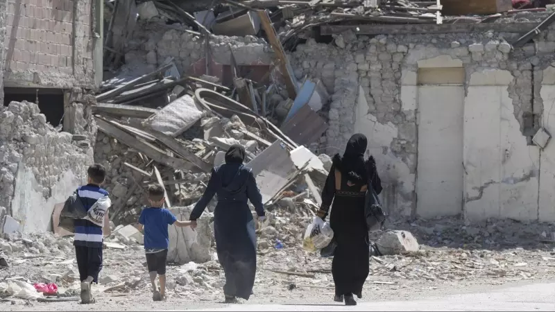 Imagen de archivo de un dos mujeres y dos niños caminando entre los escombros de uno de los 6.000 edificios que derrumbaron los terremotos de Turquía en febrero de 2023.