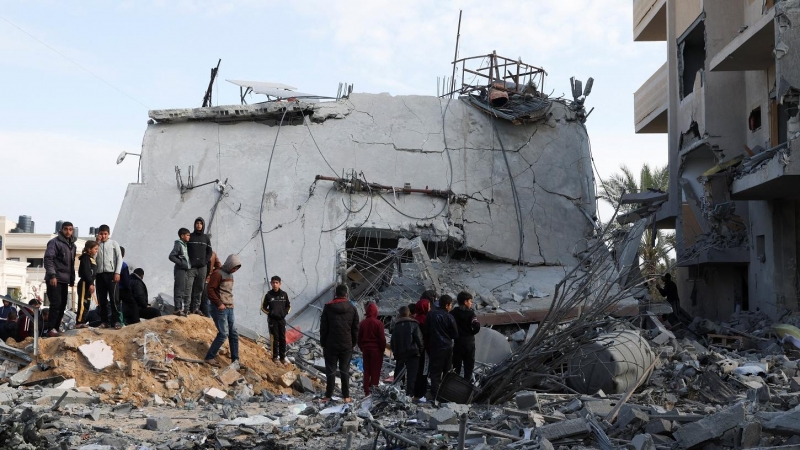 Un grupo de palestinos cerca de una casa derruida por un ataque israelí, en Rafah, en el sur de la Franja de Gaza. REUTERS/Ibraheem Abu Mustafa