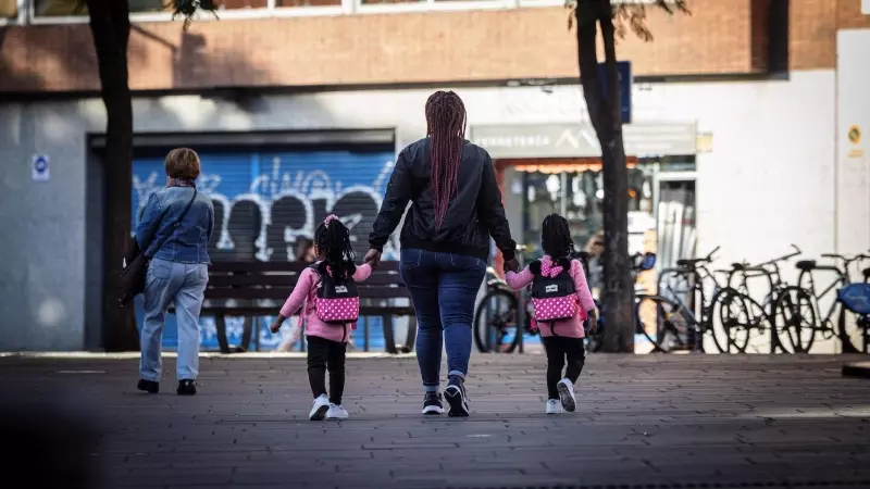 Una noia acompanya dues criatures per un carrer de Barcelona