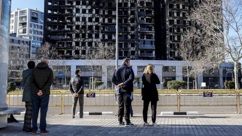 Varias personas observan el edificio incendiado del barrio de Campanar, a 24 de febrero de 2024, en Valencia