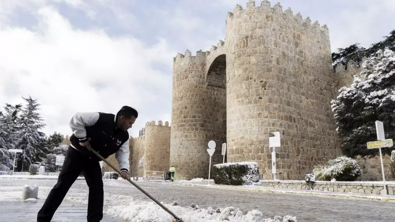 Un hombre limpia la calle de nieve frente a las murallas de Ávila (España) el 3 de marzo de 2024.