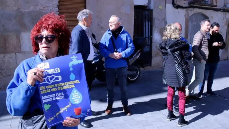 Una activista de la PDE morta un cartell de la 19a assemblea de l'entitat, amb representants del movimebnt social, econòmics i polítics parlant davant la delegació de la Generalitat, a Tortosa