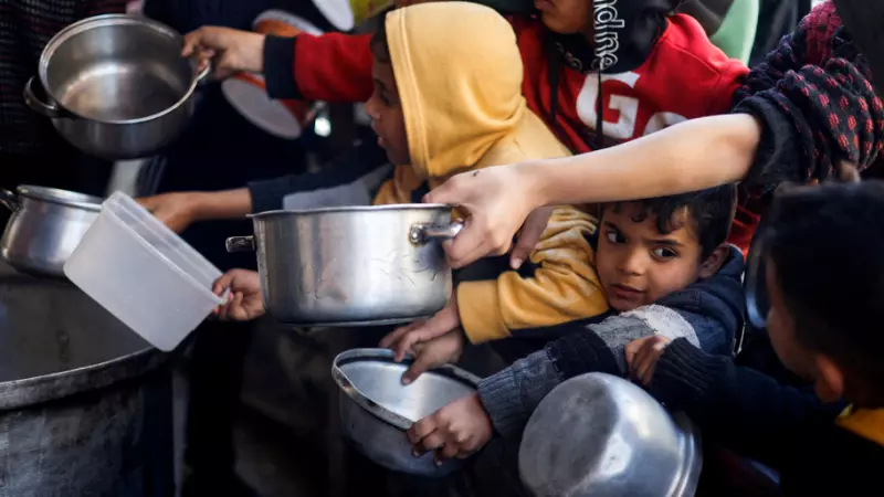 Un grupo de niños palestinos espera para recibir comida y ayuda humanitaria.