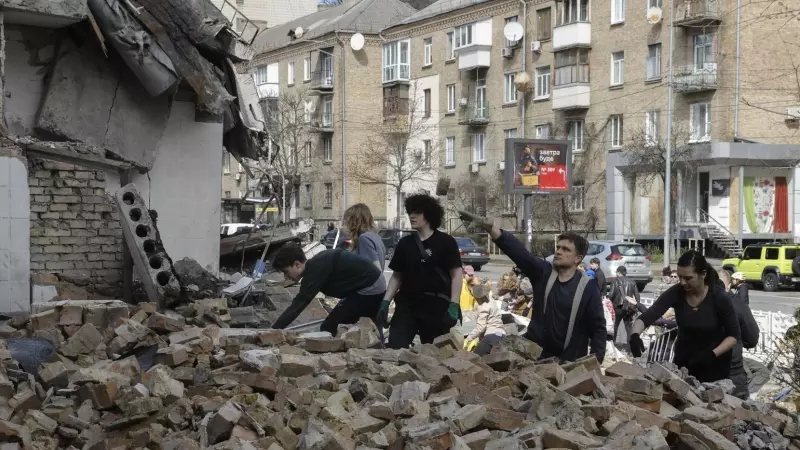 Un grupo de voluntarios trabaja entre los escombros de una academia ucraniana tras un ataque ruso.