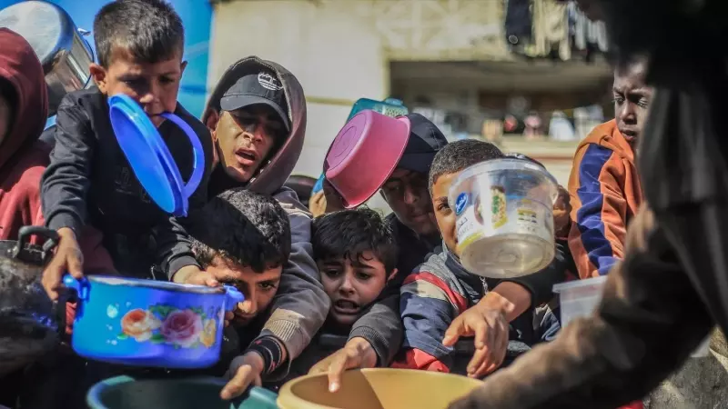 04/04/2024 Niños palestinos reciben alimentos preparados en una cocina benéfica, a 31 de diciembre de 2023.