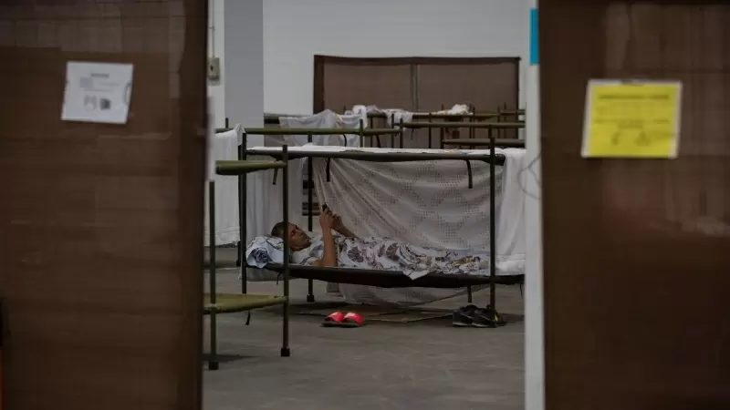 Un hombre descansa en su cama en el interior de las instalaciones del albergue de Fira Barcelona, habilitado por la pandemia para 225 personas sin techo, a 28 de marzo de 2020.