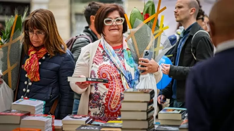 Una dona amb una rosa i el llibre de Carles Porta en una parada al centre de Barcelona per Sant Jordi