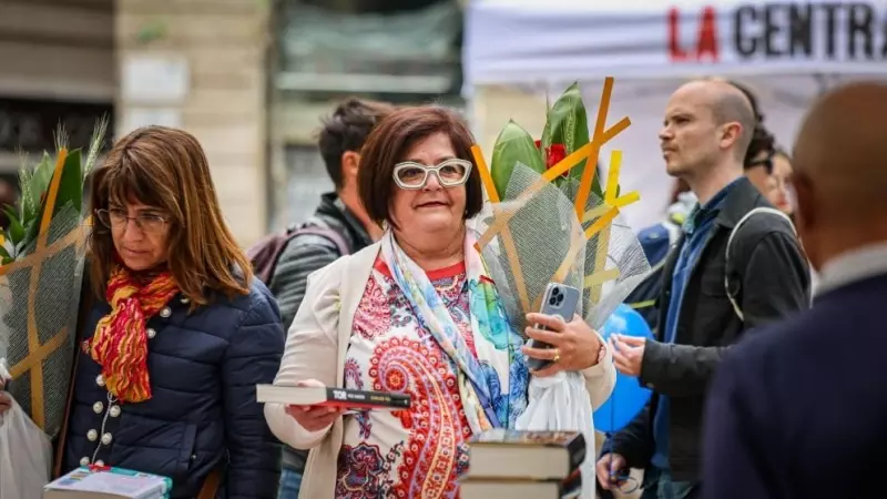 Una dona amb una rosa i el llibre de Carles Porta en una parada al centre de Barcelona per Sant Jordi