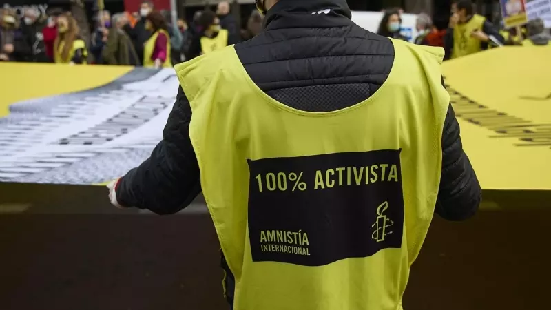 Varias personas portan una banderola amarilla gigante de Amnistía Internacional  en una manifestación, a 13 de febrero de 2022, en Madrid.