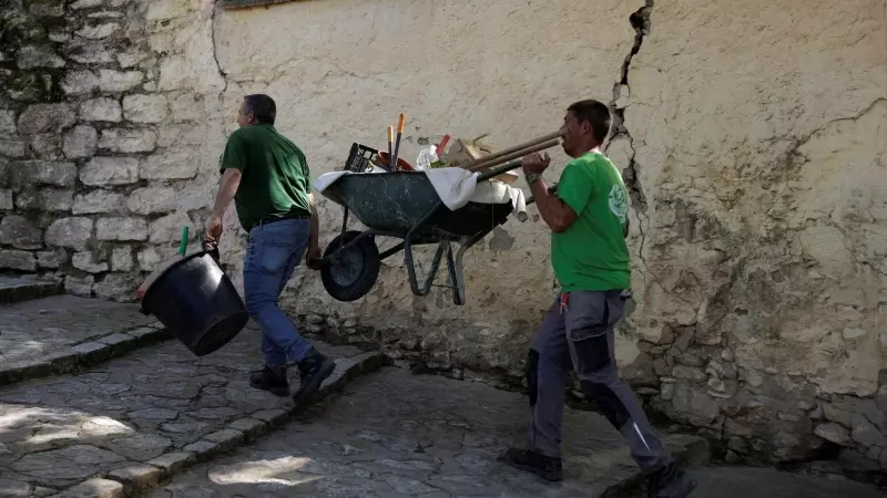 Un par de trabajadores cargan con una carretilla en una calle empinada de la localidad malagueña de Ronda. REUTERS/Jon Nazca