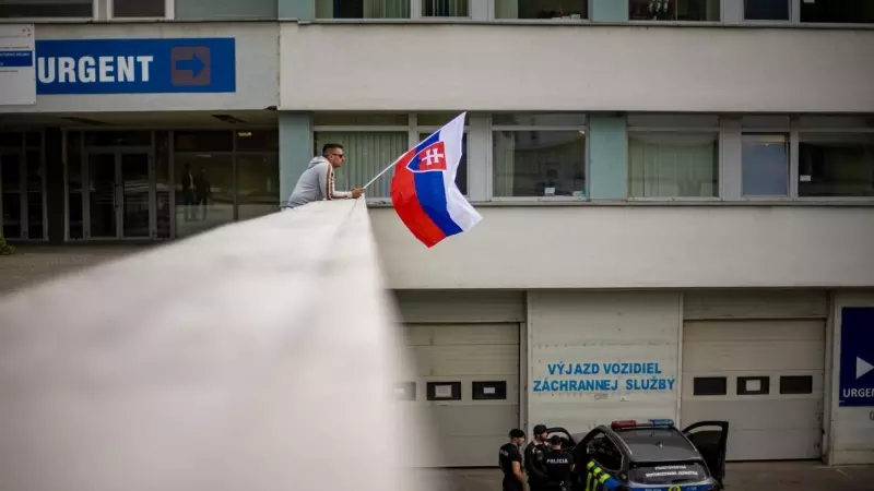 Un hombre ondea la bandera nacional eslovaca frente al hospital donde el primer ministro eslovaco, Robert Fico, está siendo tratado después de recibir varios disparos el pasado 15 de mayo.