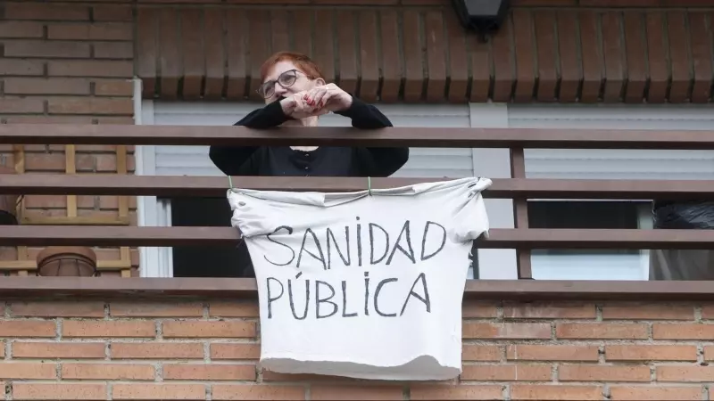 Una vecina coloca una pancarta que reza 'Sanidad Pública' para apoyar una manifestación por la sanidad pública en Villa de Vallecas, a 5 de marzo de 2023, en Madrid (España).