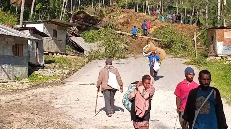 Varias personas caminan con sus pertenencias tras el desprendimiento de tierra en Kaokalam, en Papúa Nueva Guinea.