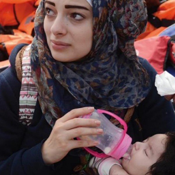 Una madre alimenta a su hija después de llegar en una balsa a la isla griega de Lesbo.