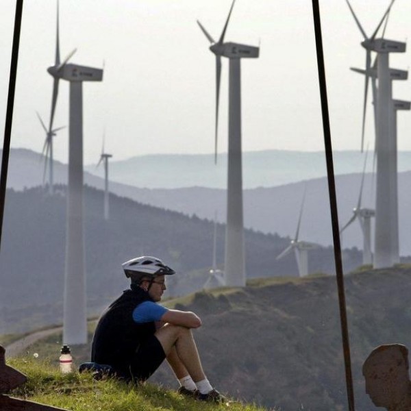 Un ciclista descansa en la Sierra del Perdón, Pamplona, con un paisaje dominado por aerogeneradores eólicos.