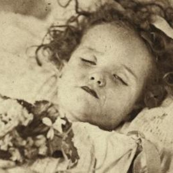 Retrato de una niña fallecida con un vestido y un ramo de flores entre las manos. - Cedida