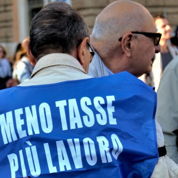 Un seguidor asiste al mitin con un chaleco en el que pide menos impuestos y más trabajo.