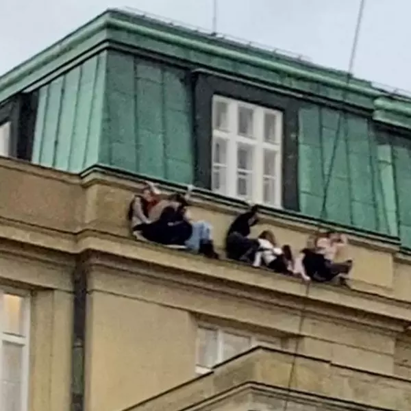 Un grupo personas se refugia en una cornisa tras el tiroteo en la Universidad Carolina, en Praga, a 21 de diciembre de 2023.