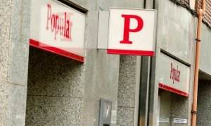 Una mujer usa un cajero automático en una oficina del Banco Santander junto a una sucursal del Banco Popular. REUTERS/Albert Gea