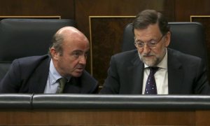 El equipo económico de Rajoy, con Luis de Guindos a la cabeza, siempre sostuvo que el rescate no iba a costarle dinero al Estado. En la imagen, el entonces ministro de Economía con el presidente del Gobierno en el Congreso de los Diputados. EFE