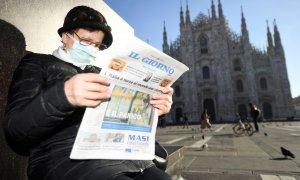 24/02/2020- Una mujer con mascarilla lee el diario 'Il Giorno' frente a la catedral de Milan (Italia). / REUTERS