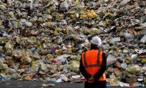 Un operario observa parte de los residuos prensados en una planta de reciclaje. /AFP