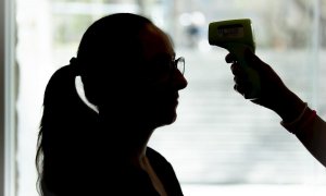 La recepcionista de una cadena de gimnasios de Barcelona toma la temperatura a una clienta antes de permitirle la entrada al establecimiento como medida preventiva para evitar el contagio del coronavirus. EFE/Enric Fontcuberta