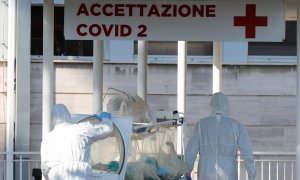 Dos sanitarios trasladan a un enfermo con coronavirus a un hospital en Roma./ REMO CASILLI (REUTERS)