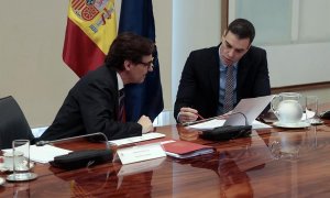 Fotografía facilitada por Moncloa que muestra al presidente del Gobierno, Pedro Sánchez (d) mientras conversa con el ministro de Sanidad, Salvador Illa (i) durante la videoconferencia de presidentes autonómicos tras haber anunciado una nueva prórroga del