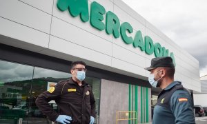 Un vigilante jurado y un guardia civil, ambos con mascarillas, delante de una tienda de Mercadona en Pamplona. E.P./Eduardo Sanz